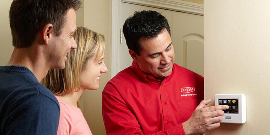 Technician showing couple how to control thermostat